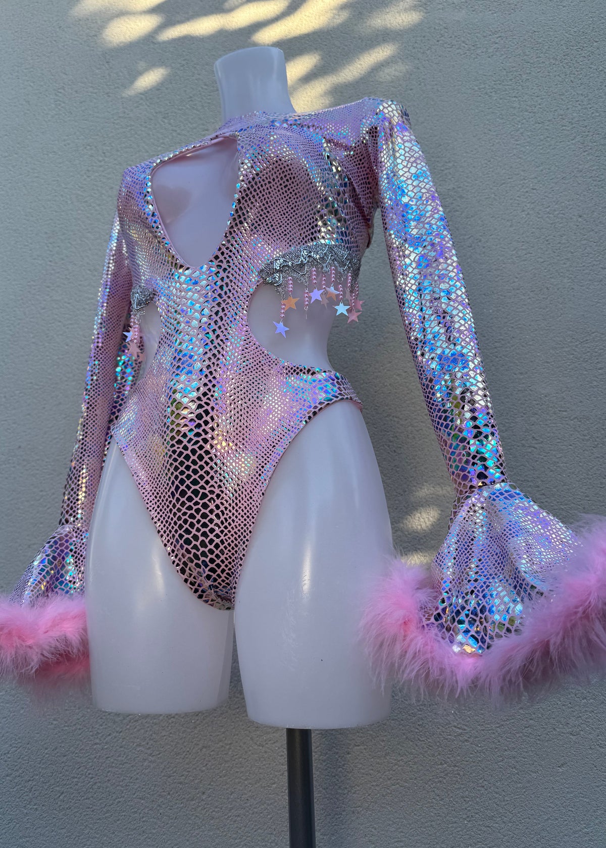 Sparkly costume with pink feather accents on a mannequin against a neutral background